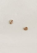 Pair of gold spiral earrings on a light beige background
